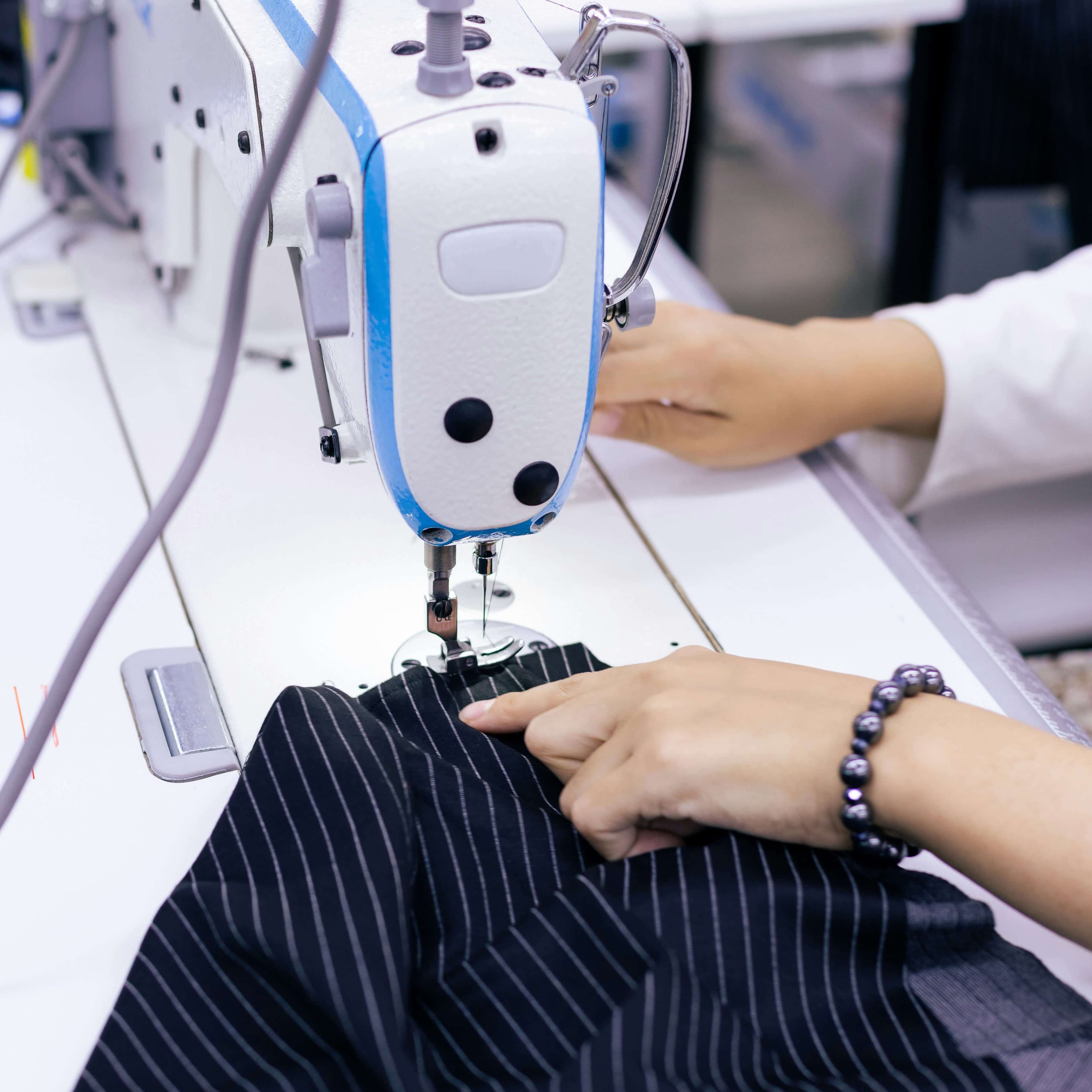 Modista cosiendo prenda en taller de costura en Prosperidad, Madrid